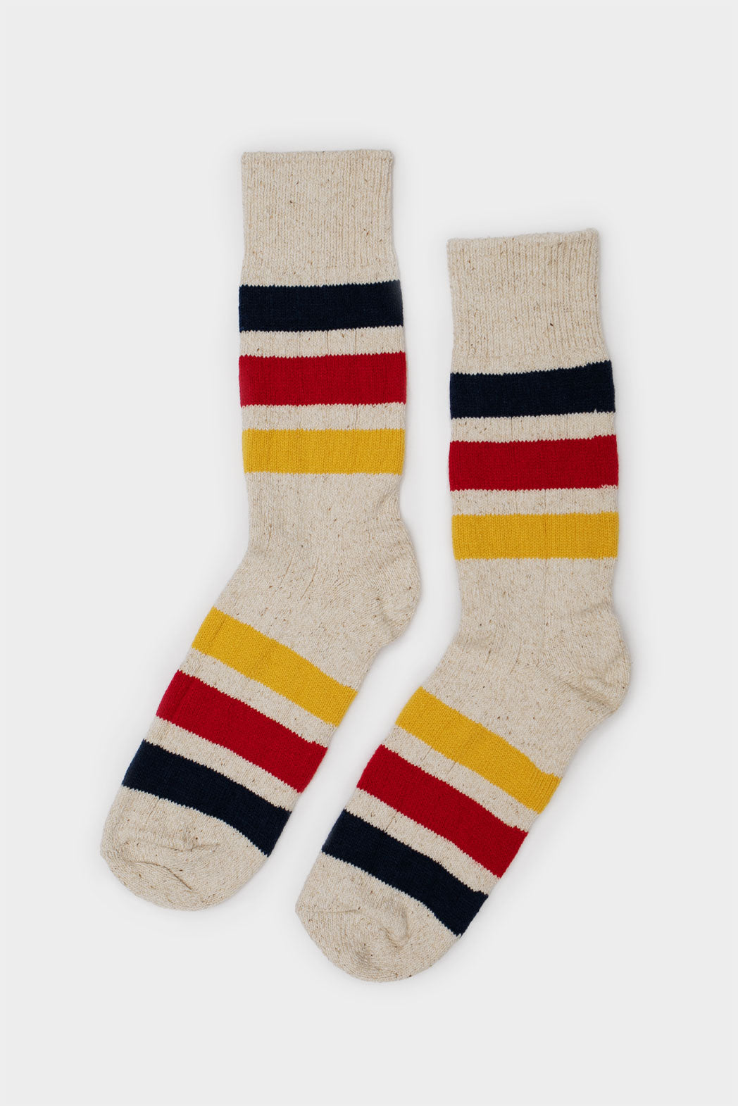 A pair of RoToTo Park Stripe Crew Socks in ivory with chunky navy blue, red, and yellow stripes, displayed side by side against a plain white background.